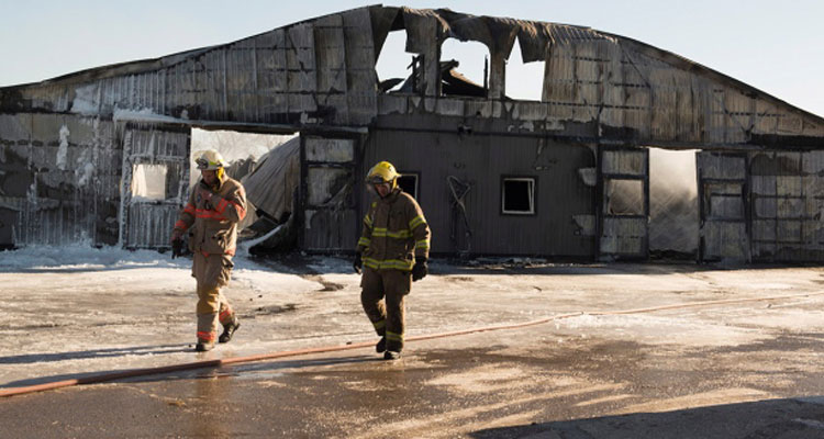 Firefighters walk past a barn that was destroyed by a fire at the Classy Lanes Stables in Puslinch, Ont., on Tuesday, Jan. 5, 2016. (Hannah Yoon / THE CANADIAN PRESS)