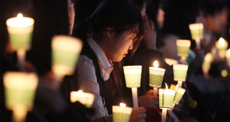 A high school student holds a candle to pay her respect to the victims of the sunken ferry Sewol during a ceremony on the eve of the second anniversary of the ferry sinking in Ansan, South Korea, Friday, April 15, 2016. (AP / Ahn Young-joon)